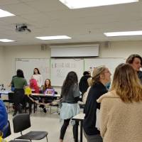 Students and professors discussing art in Spanish in a classroom